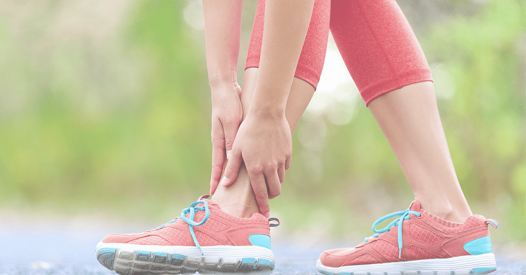 a person holding their ankle in support after sprain.a person holding their ankle in support after sprain.